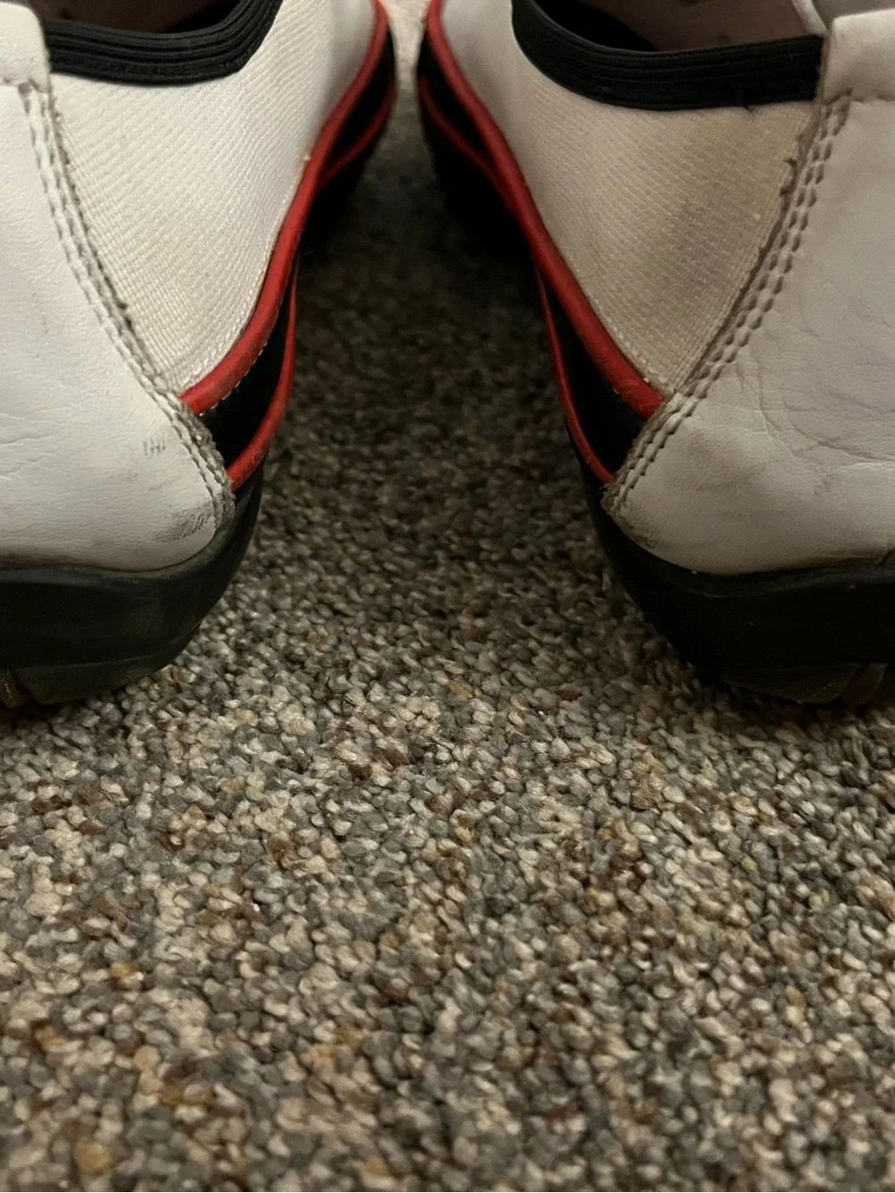 Donald J Pliner white canvas and black leather sneakers with red trim.